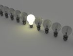 A row of light bulbs, with only the center bulb lit.